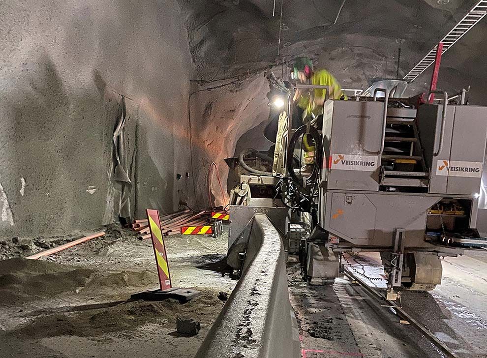 arbeidere støper betongrekkverk i tunell med bistand av maskiner