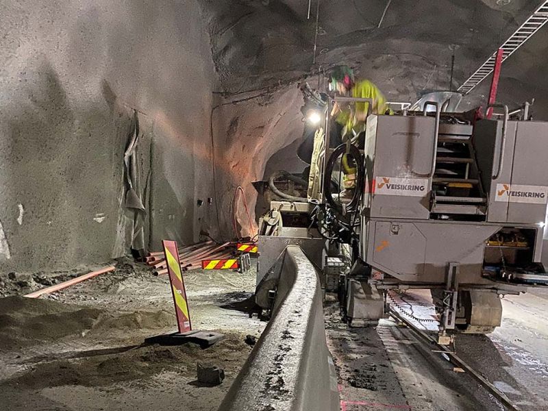 arbeidere støper betongrekkverk i tunell med bistand av maskiner